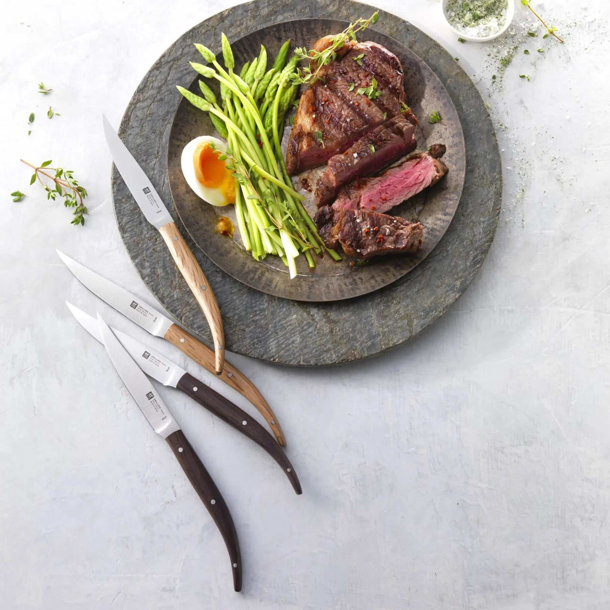 Ensemble de 4 couteaux à steak Toro ZWILLING avec manches variés en palissandre, chêne vert et Micarta, lames en acier NITRIUM durable, présentés dans coffret en bois élégant.