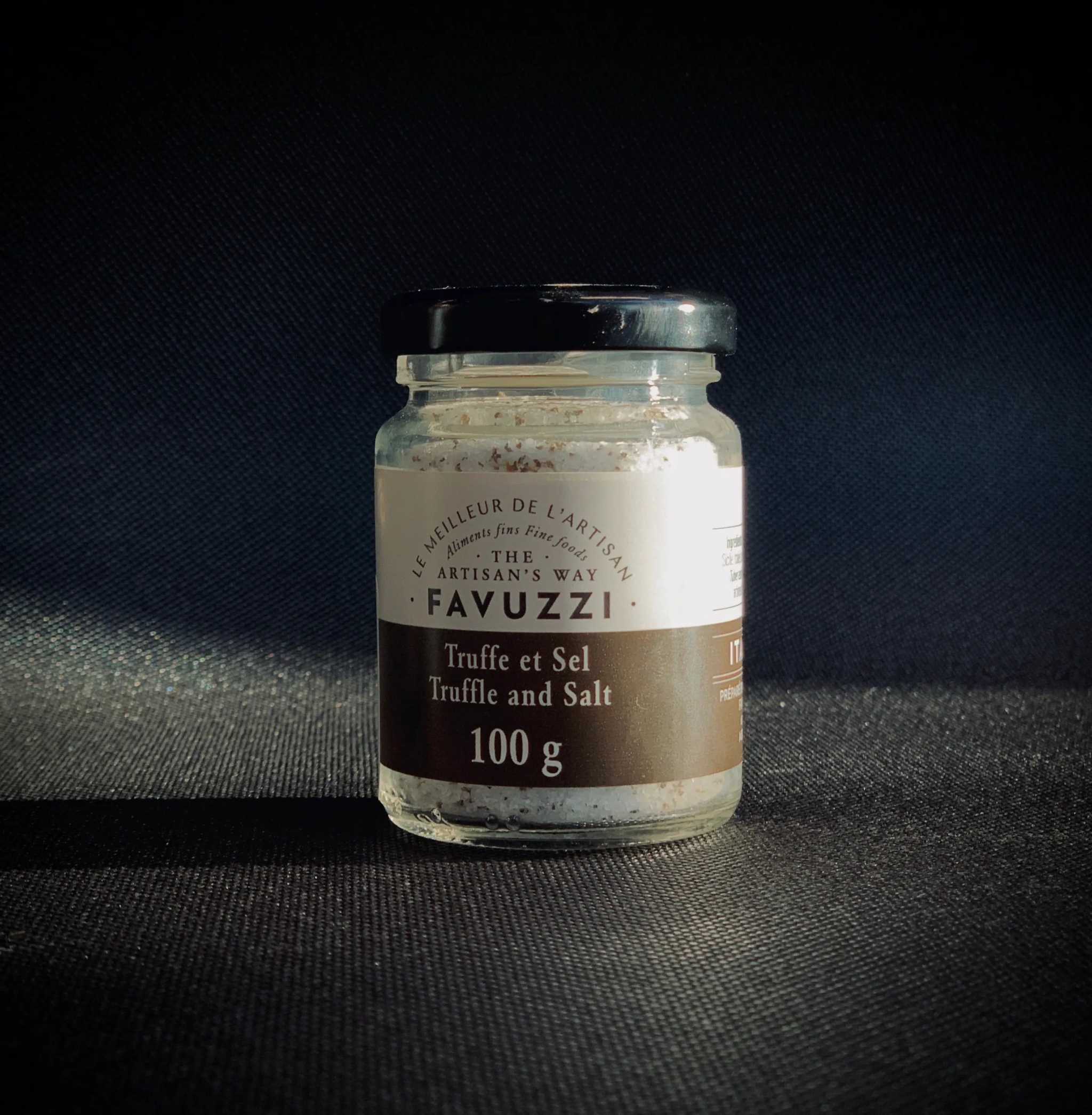 Jar of Favuzzi Sel à la truffe with fine sea salt and summer truffle pieces on black background